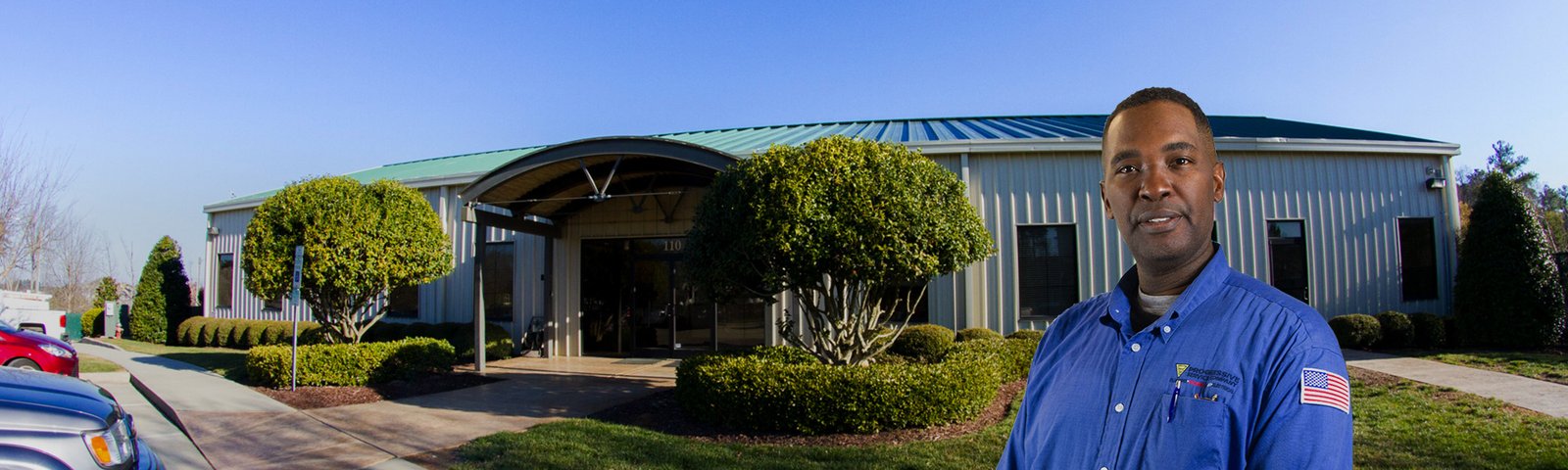 Man in a blue uniform standing outside a modern building.